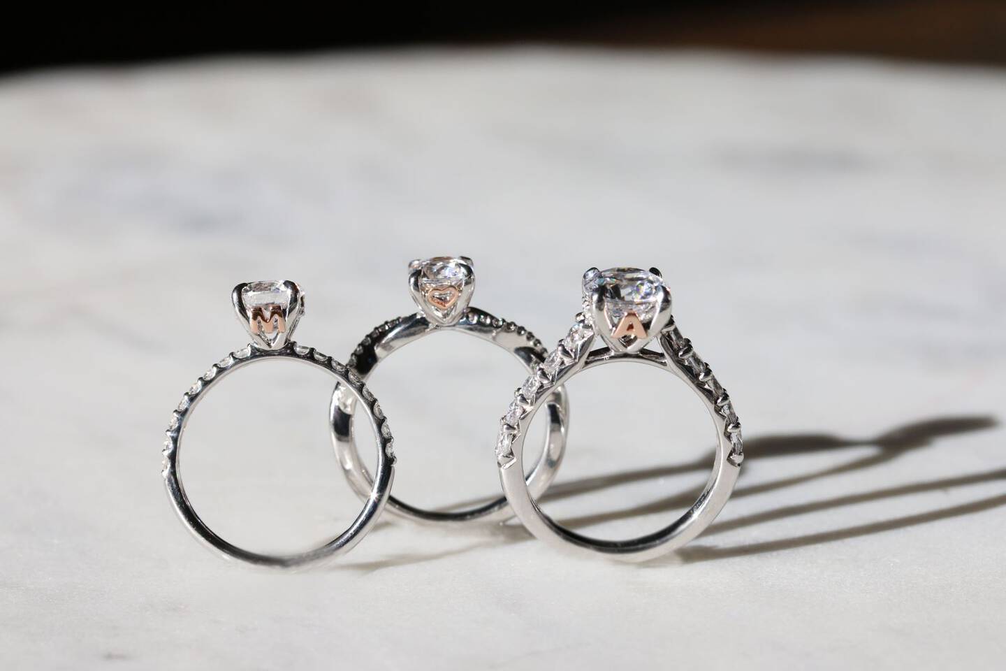 A diamond solitaire ring in white gold is balanced on a white surface